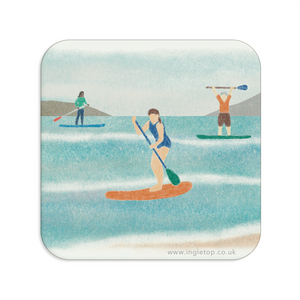 A square coaster with rounded corners, with an illustration of three paddle boarders on the water