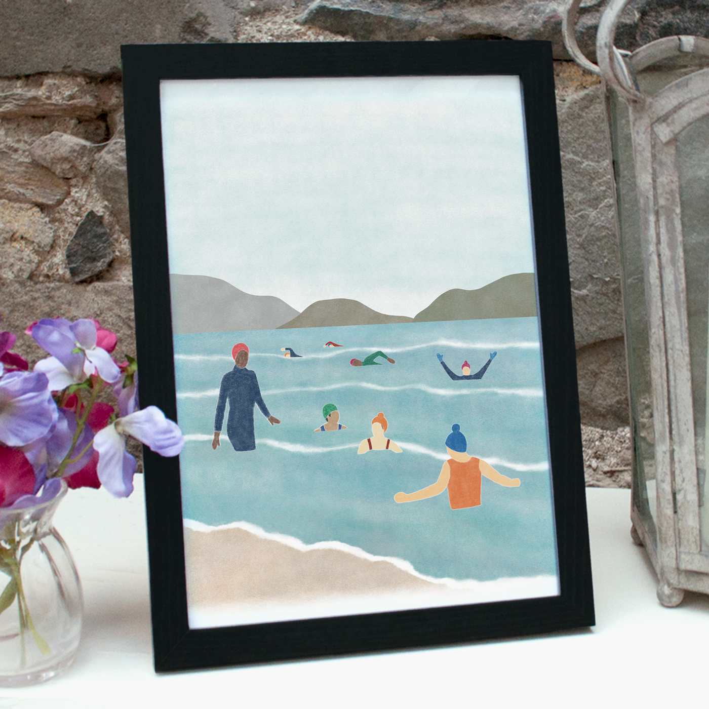 Wild swimming print, an illustration of eight people swimming in the sea, in a black frame standing on a shelf 